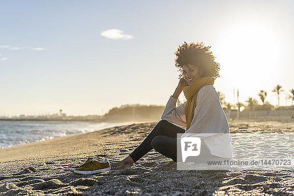 Frau sitzt bei Sonnenuntergang am Strand
