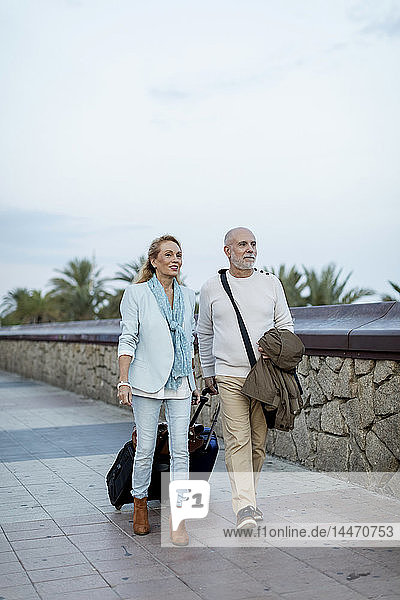 Spain  Barcelona  senior couple walking with baggage on the promenade