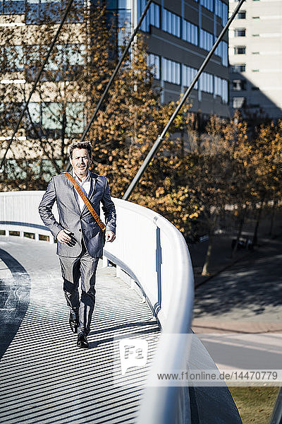 Businessman wearing full suit  running on a bridge