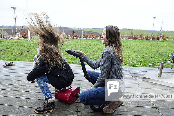 Zwei Freunde spielen mit dem Gebläse auf der Terrasse