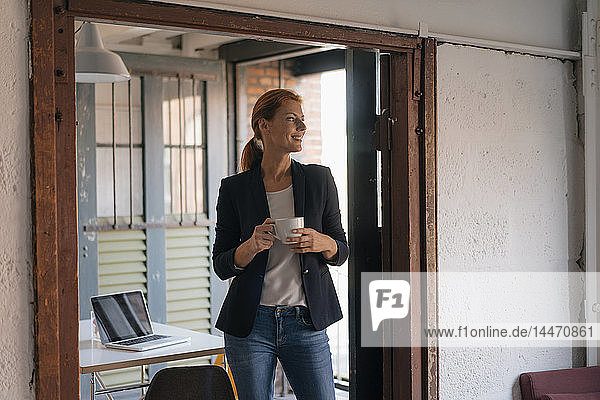 Lächelnde Geschäftsfrau bei einer Kaffeepause im Büro