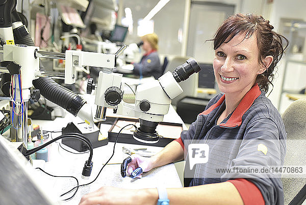 Porträt einer lächelnden Frau  die an der Qualitätskontrolle bei der Herstellung von Leiterplatten für die Elektronikindustrie arbeitet