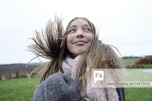 Porträt eines lächelnden Mädchens mit wehendem Haar im Winter mit Blick nach oben
