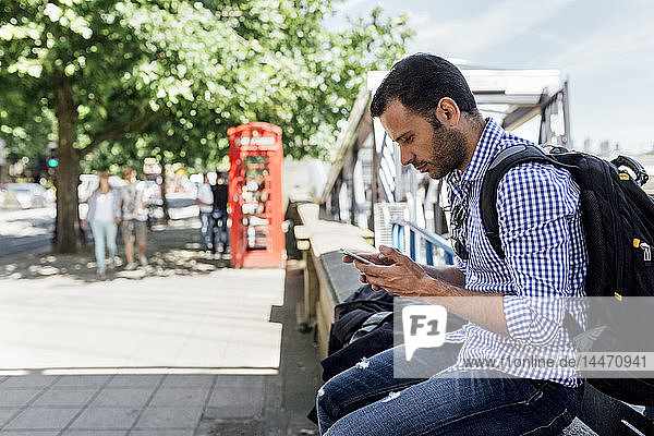 Großbritannien  London  Mann benutzt sein Smartphone auf der Straße