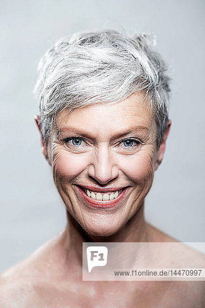 Bildnis einer lachenden  reifen Frau mit kurzen  grauen Haaren und blauen Augen