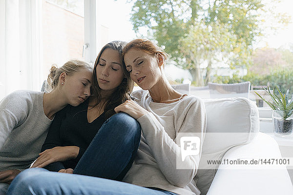 Mutter mit zwei Teenager-Mädchen  die sich zu Hause auf der Couch entspannen