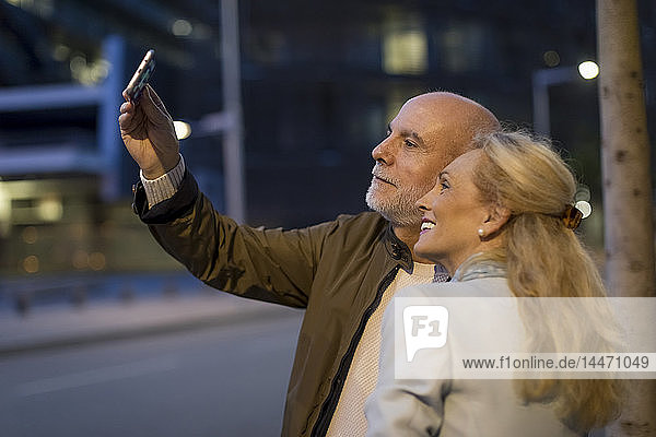 Spain  Barcelona  happy senior couple taking a selfie in the city at dusk