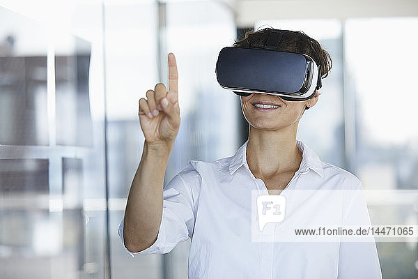 Geschäftsfrau mit VR-Brille im Büro hebt den Finger