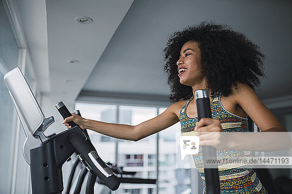 Smiling young woman on step machine in gym