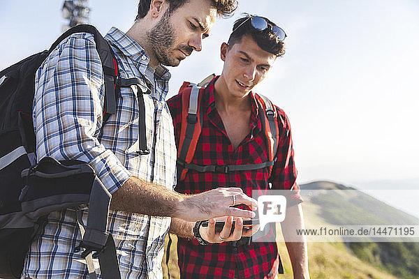 Italien  Monte Nerone  zwei Männer beim Wandern und beim Blick auf das Smartphone in den Bergen