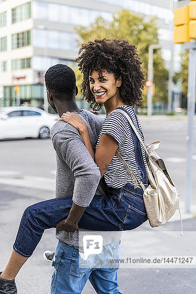 Young man carrying his girlfriend piggyback in the street