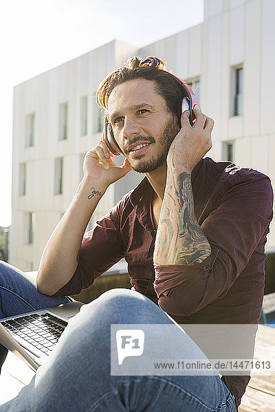 Mann auf einer Dachterrasse  der mit seinen Kopfhörern Musik hört