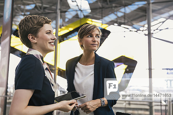 Lächelnder Fluglinienangestellter mit Tablette und Geschäftsfrau am Flughafen