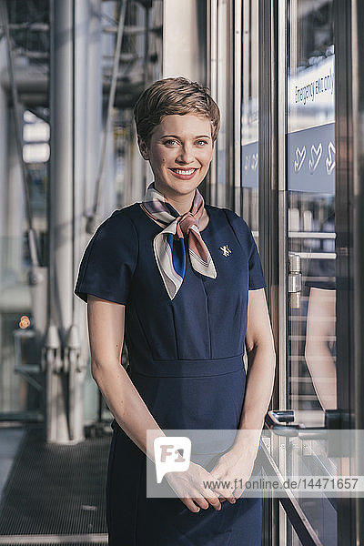 Porträt eines lächelnden Mitarbeiters einer Fluggesellschaft  der am Fenster des Flughafens steht