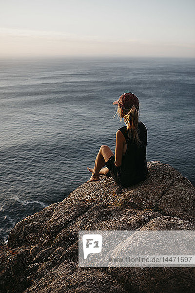 Südafrika  Westkap  Frau sitzt auf einem Felsen und schaut auf die Aussicht