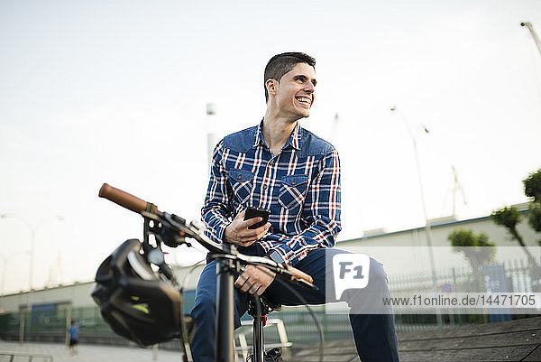 Happy young man with bicycle and cell phone
