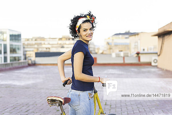 Porträt einer lächelnden jungen Frau mit Fahrrad in der Stadt
