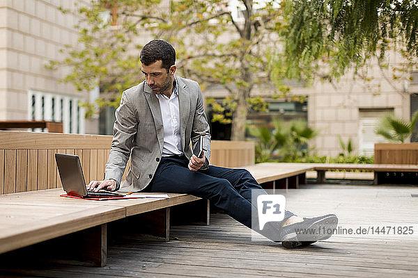 Businessman sitting on a bench using laptop