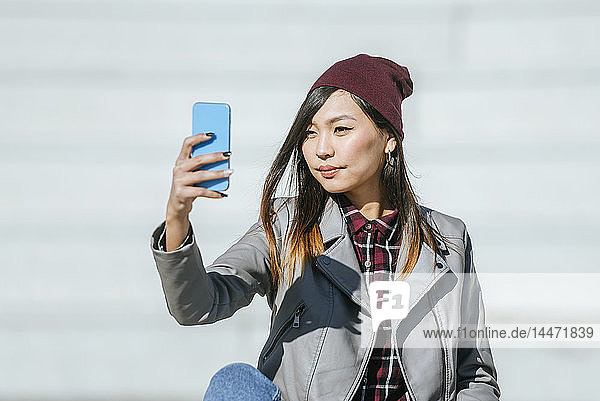 Porträt einer jungen Frau  die mit einem Smartphone Selbsthilfe betreibt