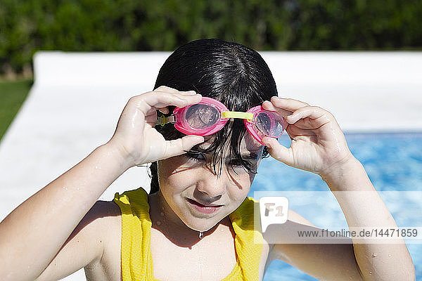 Portrait of little girl wearing swimming goggles at pool