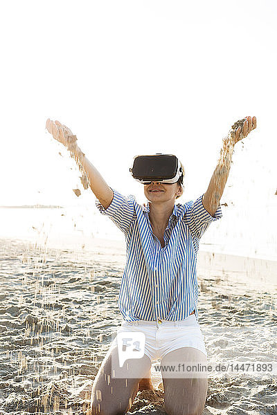 Thailand  Frau mit Virtual-Reality-Brille am Strand im Morgenlicht