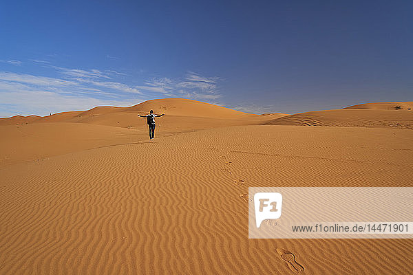 Morocco  back view of man with backpack standing on desert dune