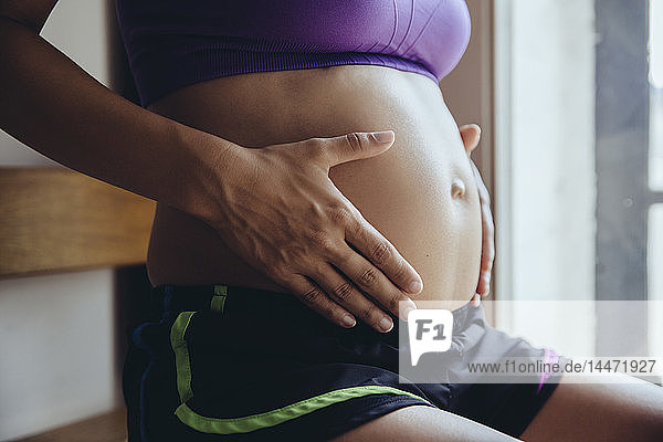 Sportliche schwangere Frau hält ihren Bauch