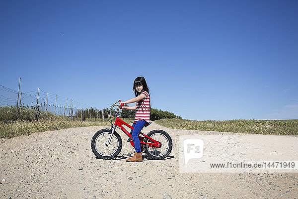 Girl with bicycle on path in remote landscape