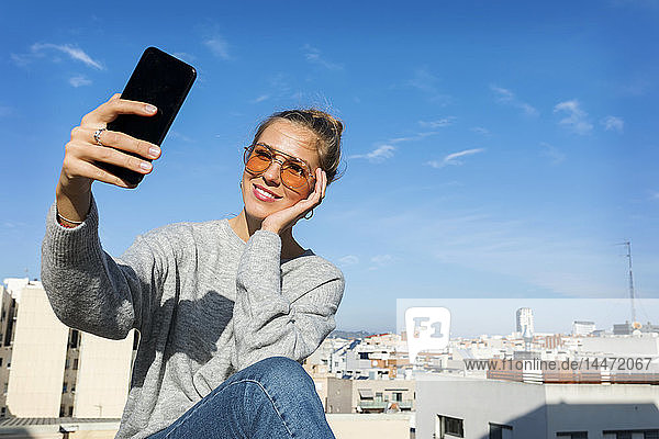 Junge Frau nimmt Smartphone-Selbstbedienung auf einer städtischen Dachterrasse
