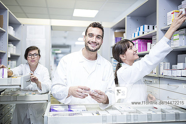 Smiling pharmacists working at cabinet in pharmacy