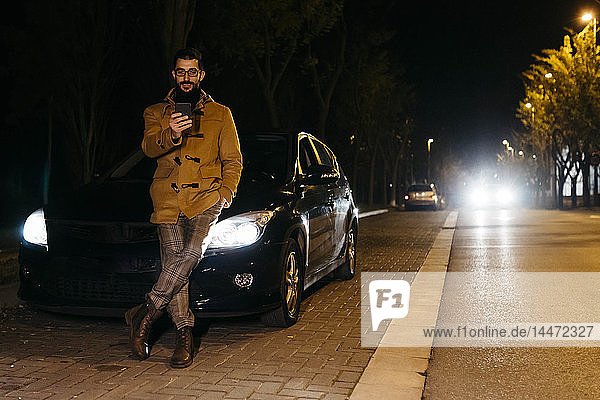 Spanien  Igualada  Mann benutzt nachts sein Handy vor dem Auto