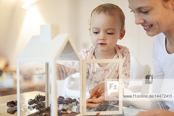 Mutter und kleine Tochter basteln zu Hause an herbstlich dekorativem Haus