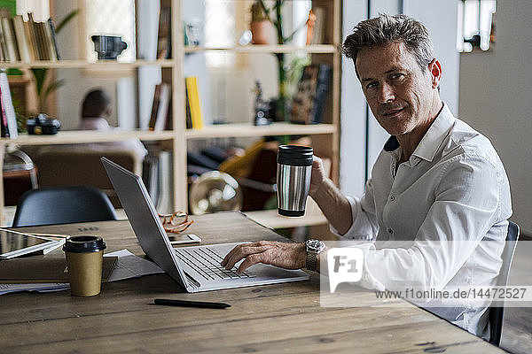 Portrait of businessman using laptop at desk