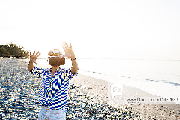 Thailand  Rayong  Frau mit Virtual-Reality-Brille am Strand