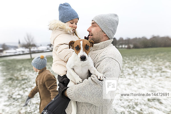 Vater mit zwei Kindern und Hund in Winterlandschaft