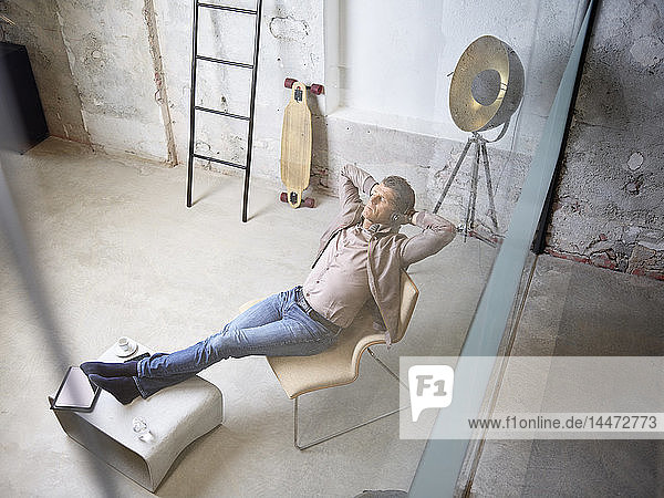 Relaxed businessman listening to music in office lounge