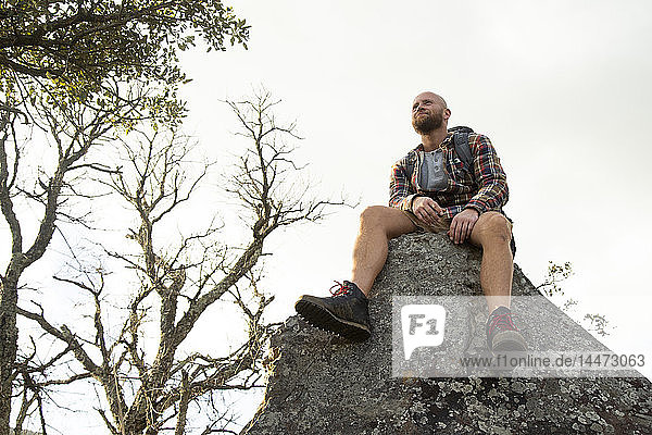 Spain  Andalusia  Tarifa  smiling man on a hiking trip having a break sitting on rock