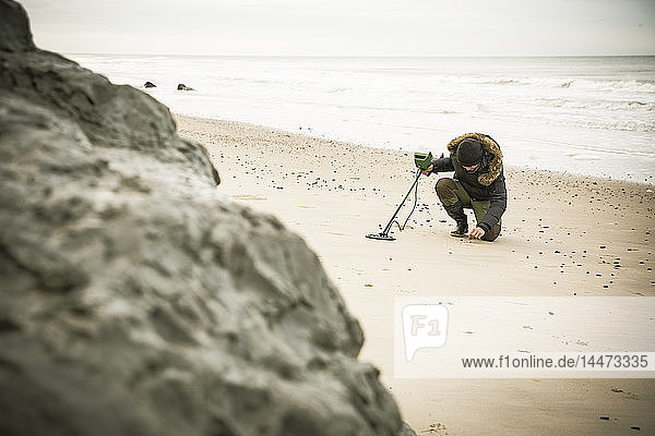Mann mit Metalldetektor am Sandstrand