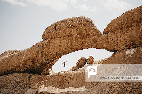 Namibia  Spitzkoppe  Frau springt auf Felsformation
