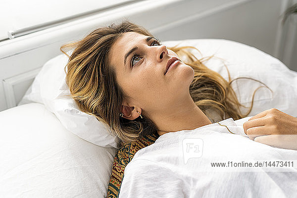 Porträt einer schönen jungen Frau im Bett liegend