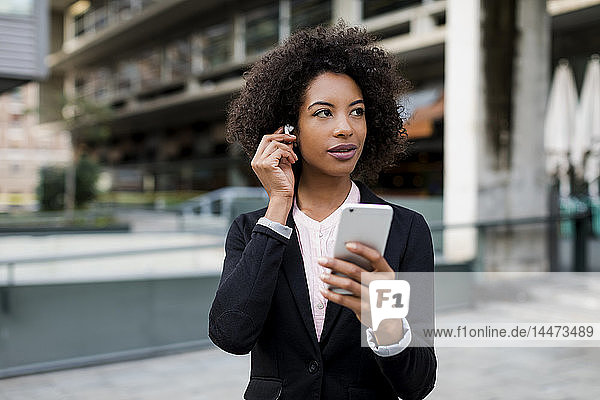 Porträt einer Geschäftsfrau mit einem Smartphone und Kopfhörern