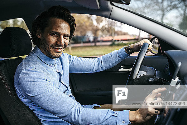 Porträt eines lächelnden Geschäftsmannes beim Autofahren mit einem Mobiltelefon als Navigationssystem