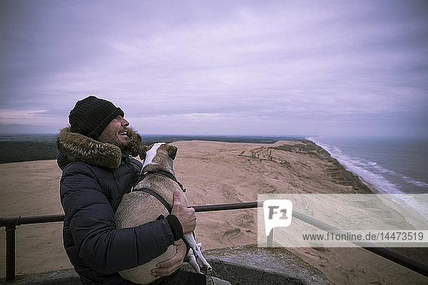 Dänemark  Nordjütland  Leuchtturm Rubjerg Knude  lachender Mann und sein Hund zur blauen Stunde