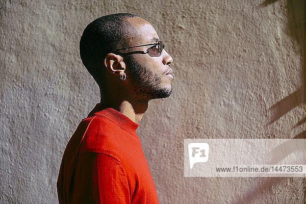 Profile of young man wearing sunglasses and red pullover at sunlight