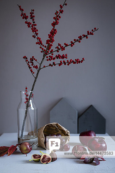 Stechpalmenzweig in Vase  rote Früchte und Herbstblätter