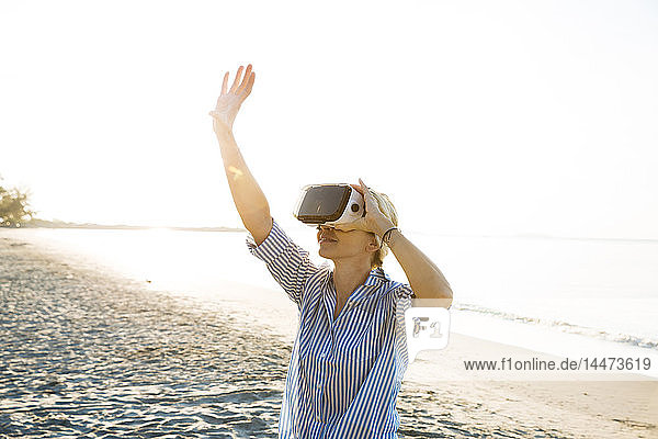 Thailand  woman using virtual reality glasses on the beach in the morning light