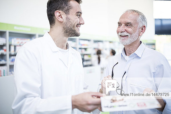 Pharmacist smiling at mature man in pharmacy