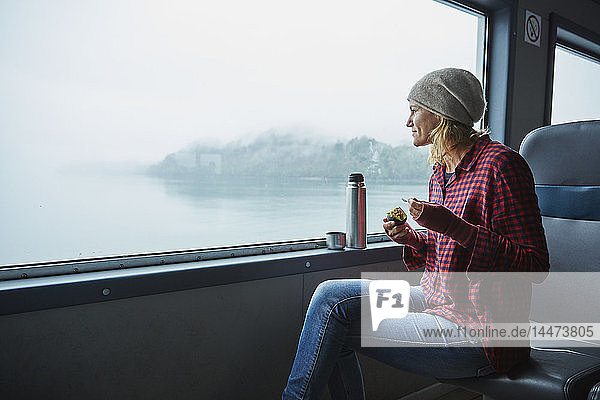 Chile  Hornopiren  Frau  die aus dem Fenster einer Fähre schaut und eine Avocado isst