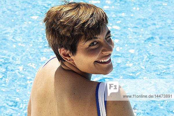 Porträt einer zwinkernden jungen Frau im Schwimmbad