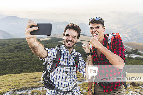 Italy  Monte Nerone  two happy hikers on top of a mountain taking a selfie